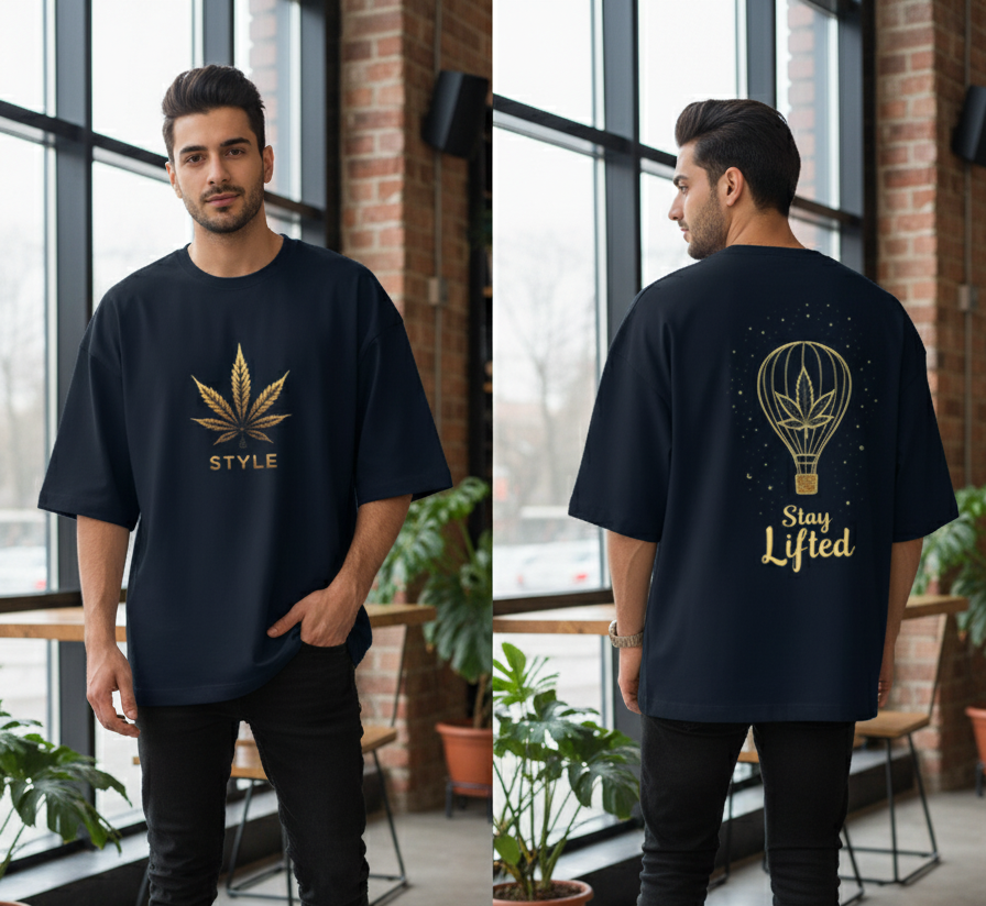 Man wearing a black t-shirt with a gold cannabis leaf design and text, indoors.